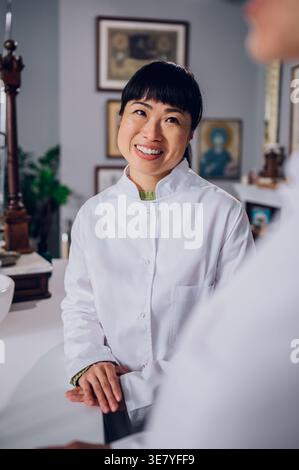 Japanische Apothekerin im Laborkittel, die mit einer kaukasischen Kollegin in der Vintage-Apotheke steht Stockfoto