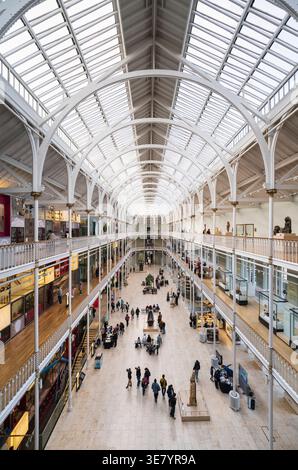 Die riesige, lichtdurchflutete Halle des National Museum of Scotland zeigt mehrere Ausstellungsebenen und eine Menge von Menschen, die die Ausstellungen genießen Stockfoto