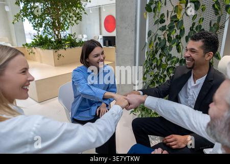 Schwarzer Mann mit kaukasischen Kollegen, die während der Psychotherapiesitzung auf Stühlen sitzen Stockfoto