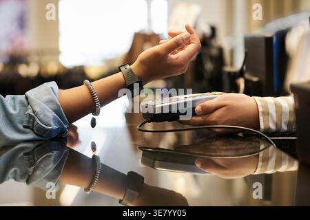 Nahaufnahme der Hände der Schwarzen Frau, die digitale Armbanduhr abklopfen, um im Bekleidungsgeschäft zu bezahlen Stockfoto