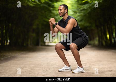 Schwarzer Mann mit Sportbekleidung und Ohrhörern, der tagsüber im Freien trainiert Stockfoto