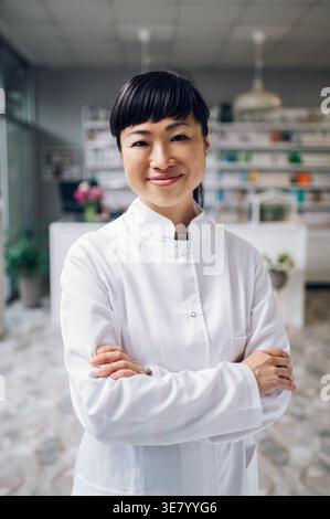Japanische Apothekerin steht mit gekreuzten Armen in der Apotheke Stockfoto
