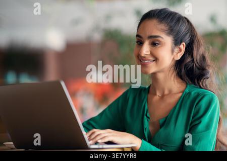 Indische Frau, die im Café am Tisch sitzt Stockfoto