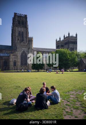 Eine Gruppe junger Leute genießt ein Picknick auf dem Gras mit der historischen Kathedrale von Durham als Kulisse Stockfoto