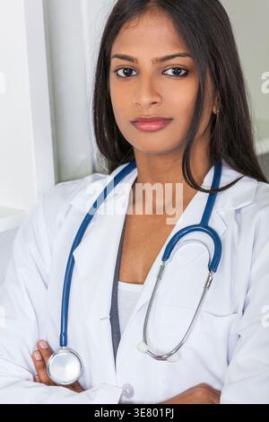 Ernsthafte indische Ärztin mit Stethoskop um den Hals stehend mit gekreuzten Armen in der Klinik Stockfoto