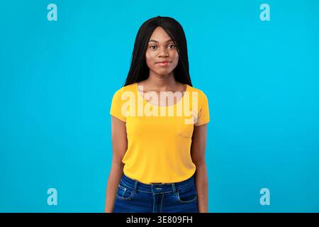Lächelnde schwarze Frau mit Wendungen, die vor blauem Hintergrund im Studio steht Stockfoto