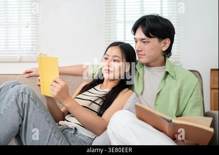 Thailändisches Paar liest Bücher auf Sofa zu Hause Stockfoto