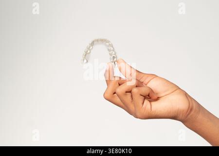 Hand eines kubanischen männlichen Teenagers mit klaren Zahnlindern vor weißem Hintergrund im Atelier Stockfoto