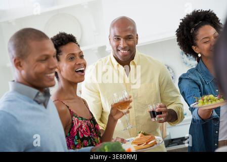 Schwarzer Geschäftsmann, der ein Glas Saft und einen Teller mit Essen hält, neben afroamerikanischen Kollegen im Büro Stockfoto
