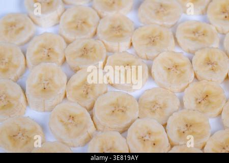 Geschnittene Bananen flach auf weißem, sauberem Gitter aus Bananenrunden, weiches natürliches Licht, minimales Küchendesign für Smoothie-Schüssel, frische Textur und dezente s Stockfoto