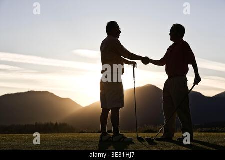 Asiatische und französische Golfer schütteln sich die Hand auf dem Golfplatz Stockfoto