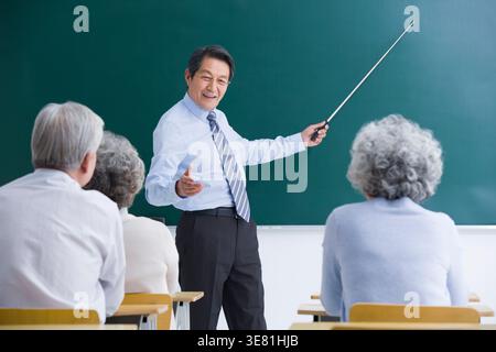 Leitender chinesischer Professor, der Oberschüler im Klassenzimmer unterrichtet Stockfoto