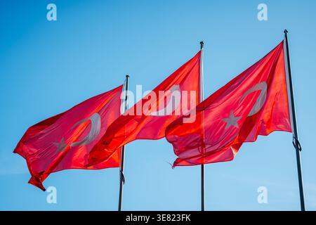 Drei Türkische Fahnen Winken Gegen Klaren Blauen Himmel, Starker Wind, Der Leuchtend Rotes Gewebe Mit Weiß Stockfoto