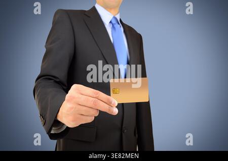Hand eines Geschäftsmannes mit goldener Kreditkarte und isoliert auf blauem Hintergrund Stockfoto