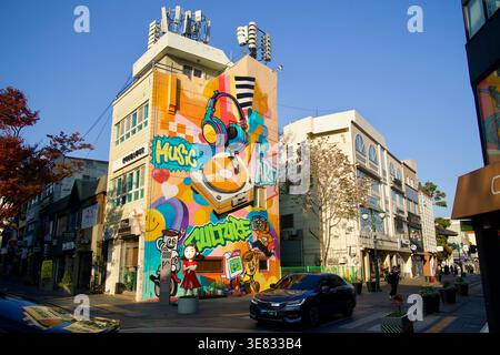 In einem Eckgebäude in Seongnam-dong befindet sich ein großes Wandgemälde mit Musikmotiven, Kopfhörern, einem Plattenspieler und Zeichentrickfiguren über der Straße im Zentrum von UL Stockfoto