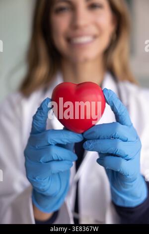 Kardiologin Frau, professionelle Ärztin, die vor der Kamera rotes Herz zeigt Stockfoto