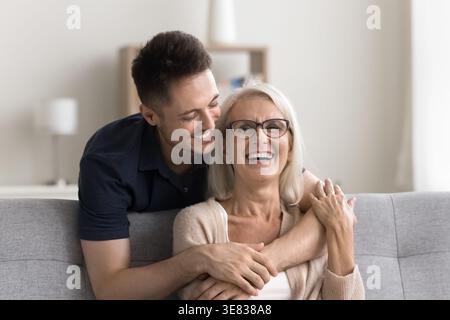 Schöne reife Frau genießt Kuscheln von liebevollem erwachsenem Sohn Stockfoto