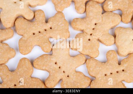 Bärenkekse aus der Nähe, die auf weißer Oberfläche gestapelt sind, zeigen eine knusprige Textur, goldenen Backkuchen und subtile Zuckerkristalle für eine handwerkliche Bäckerei Stockfoto