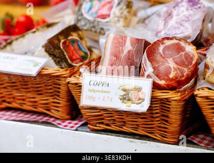 Villach, Österreich - 05. September 2025: Verschiedene Wurstwaren, einschließlich coppa, werden an einem lebhaften Marktstand in Körben wunderschön angeordnet Stockfoto