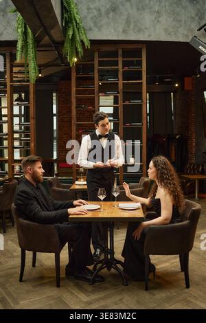 Erwachsenes Paar bestellt Abendessen beim Kellner im gehobenen Restaurant Stockfoto