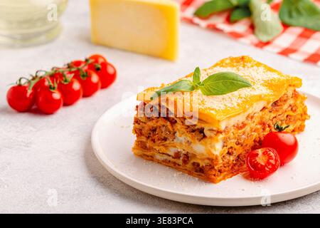 Traditionelle Lasagne mit Bolognesesauce, belegt mit Basilikumblättern, serviert auf einem weißen Teller Stockfoto