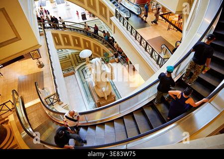 Die Leute laufen die Rolltreppen an der Shopping Mall im Caesars Palace hinunter. Käufer genießen einen geschäftigen Tag, um Geschäfte zu sehen und zu interagieren. Stockfoto
