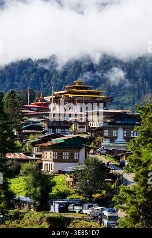 Bhutanese Gangtey Klosterkomplex zwischen Kiefernwäldern mit nebeligen Bergen und Wolken, bhutanischer Architektur, ruhiges landschaftliches Reiseziel. Stockfoto