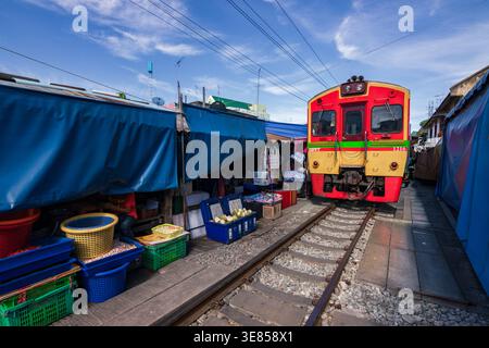 Der Zug fährt durch den Maeklong Railway Market mit Ständen und Regenschirmen, Samut Songkhram, Thailand Stockfoto
