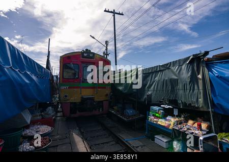 Der Zug fährt durch den Maeklong Railway Market mit Ständen und Regenschirmen, Samut Songkhram, Thailand Stockfoto