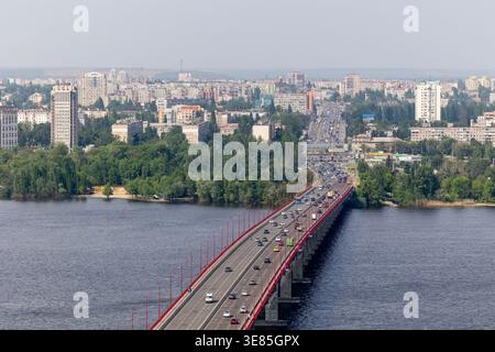 Dnipro, Ukraine – 18. Mai 2023: Ein beeindruckender Blick aus der Höhe fängt eine mehrspurige Straßenbrücke mit Autos über den breiten Fluss Dnieper ein, eingerahmt Stockfoto