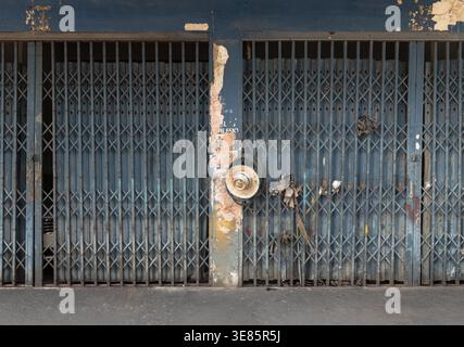 Bangkok, Thailand - 06. April 2022 - Ein verwittertes, azurfarbenes Stahlfalttor, das traditionell als Pratu Lek Yuet bekannt ist, steht als stiller Wächter der cla Stockfoto