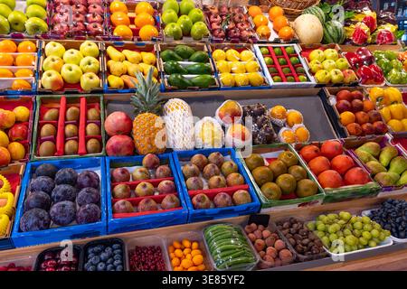 Verschiedene reife Früchte in Kisten auf einem pulsierenden Marktstand, in denen Frische, Fülle und gesunde Speisen angeboten werden. Stockfoto