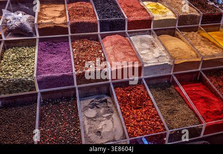 Eine Vielzahl von bunten Gewürzen, Kräutern und Gewürzen wird in transparenten Behältern an einem Marktstand ausgestellt. Stockfoto