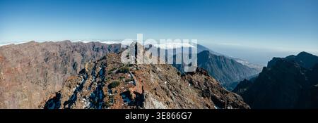 Breiter Panoramablick auf den zerklüfteten Kamm und die vulkanischen Berge bei Roque de los Muchachos, La Palma, Kanarischen Inseln, unter klarem blauem Himmel mit weiter Ferne Stockfoto