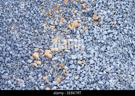 Detaillierte Textur von oben aus zerquetschtem grauen Granit, gemischt mit Sand. Kiesaggregat in Industriequalität, hergestellt als haltbare Grundlage für Straßenverkehrsanlagen Stockfoto