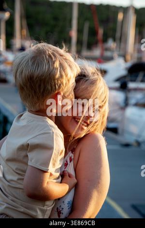 Ein zärtlicher Moment zwischen einer Mutter und ihrem Sohn, während sie sich draußen umarmen. Die freudige Interaktion fängt das Wesen familiärer Liebe und die Wärme von ein Stockfoto