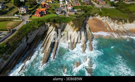 Atemberaubender Blick aus der Luft auf den Strand von Arnia in Kantabrien, Spanien. Das Bild zeigt einzigartige geologische Flysch-Formationen, türkisfarbenes Wasser und eine Küstenville Stockfoto