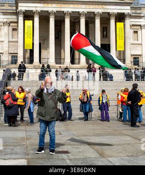 London, UK.11. April 2026. Pro-palästinensischer Demonstrant schwingt eine palästinensische Flagge und gibt gleichzeitig das Siegeszeichen. Verteidigen Sie unsere Geschworenen-Demonstration am Trafalgar Square, Zentrum von London, gegen das Verbot der Palästinensischen Aktion. Der Oberste Gerichtshof hat das Verbot der Palästinensischen Aktion für rechtswidrig befunden, aber es ist noch nicht offiziell aufgehoben worden. Im Zusammenhang mit dieser friedlichen Unterschriftenkampagne wurden bisher fast 3.000 Verhaftungen unter „Terroranklagen“ verhaftet. Quelle: Ian Humphreys/Alamy Live News Stockfoto