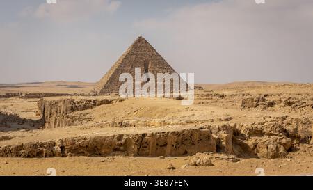Pyramide von Menkaure auf dem Gizeh-Plateau in Ägypten mit vertikaler Öffnung an der Nordfassade und Ausgrabungen davor. Stockfoto