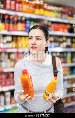 Erwachsene Frau, die Honig im Supermarkt wählt Stockfoto