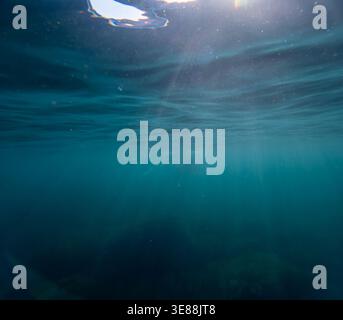 Unterwasser-Sonnenlicht Ozeanstrahlen durchdringen die blaue Wasseroberfläche und schaffen einen ruhigen und atmosphärischen Tiefseehintergrund für Naturkonzepte Stockfoto