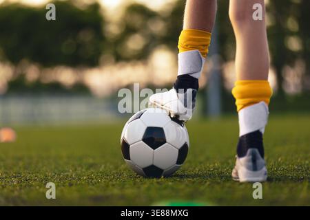 Nahaufnahme Mit Fußball-Kontrolle Für Jugendliche. Das Kind steht während des Trainings auf dem Grasfeld mit Fuß auf dem Fußball Stockfoto