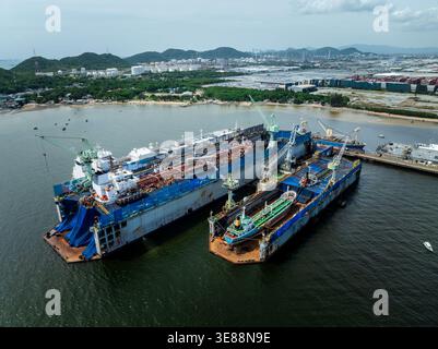 Highangle-Ansicht der maritimen Instandhaltungsarbeiten mit Frachtschiffen, die in schwimmenden Trockendocks in einem geschäftigen Hafen Rumpfreparaturen durchlaufen Stockfoto