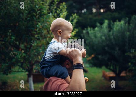 Vater hält die kleine Tochter fest, während er Zeit zusammen im Garten verbringt. Stockfoto