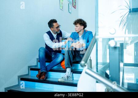 Lehrer, der sich um einen schwer wiegenden Schüler kümmert. Junge, der sich einem Lehrer anvertraut. Stockfoto