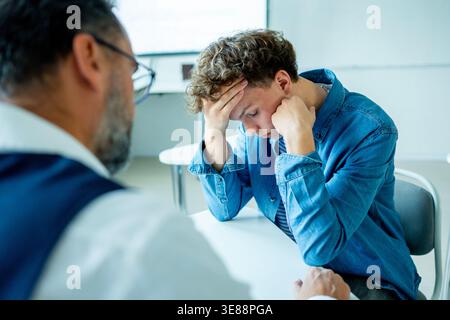 Lehrer, der sich um einen schwer wiegenden Schüler kümmert. Junge, der sich einem Lehrer anvertraut. Stockfoto