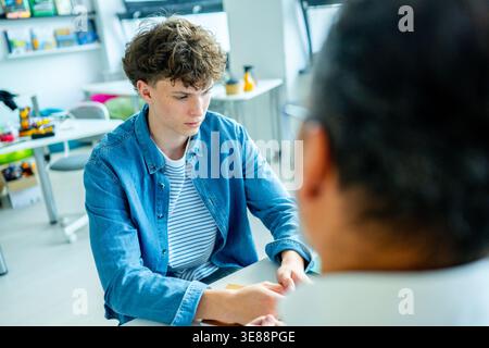 Lehrer, der sich um einen schwer wiegenden Schüler kümmert. Junge, der sich einem Lehrer anvertraut. Stockfoto