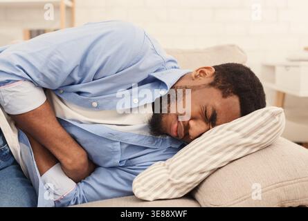 Schwarzer Mann leidet unter Magenschmerzen zu Hause Stockfoto