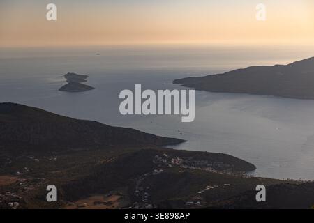 Goldenes Licht bei Sonnenuntergang taucht eine felsige Küste und zwei kleine Inseln von oben auf, das ruhige Mittelmeer und der ferne Horizont schaffen eine ruhige Atmosphäre Stockfoto