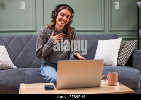 Frau, die sich auf ihrem Laptop amüsiert. Sie freut sich, mit ihren Freunden oder ihrer Familie verbunden zu sein. Stockfoto